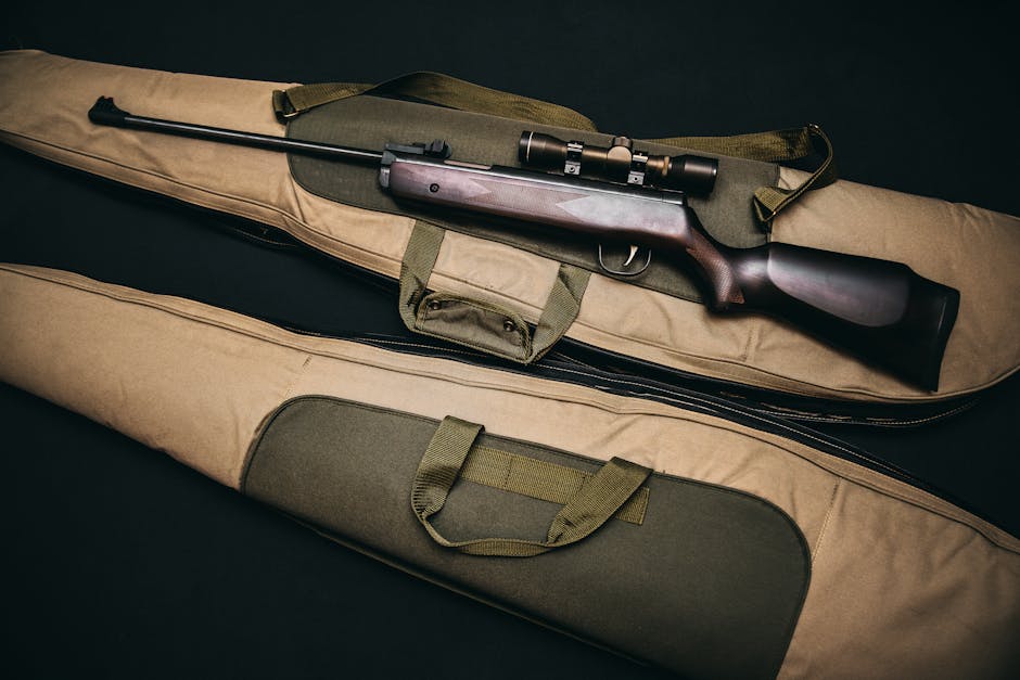 Close-up of a hunting rifle with a scope on a carrying bag, showcasing firearms and hunting gear.